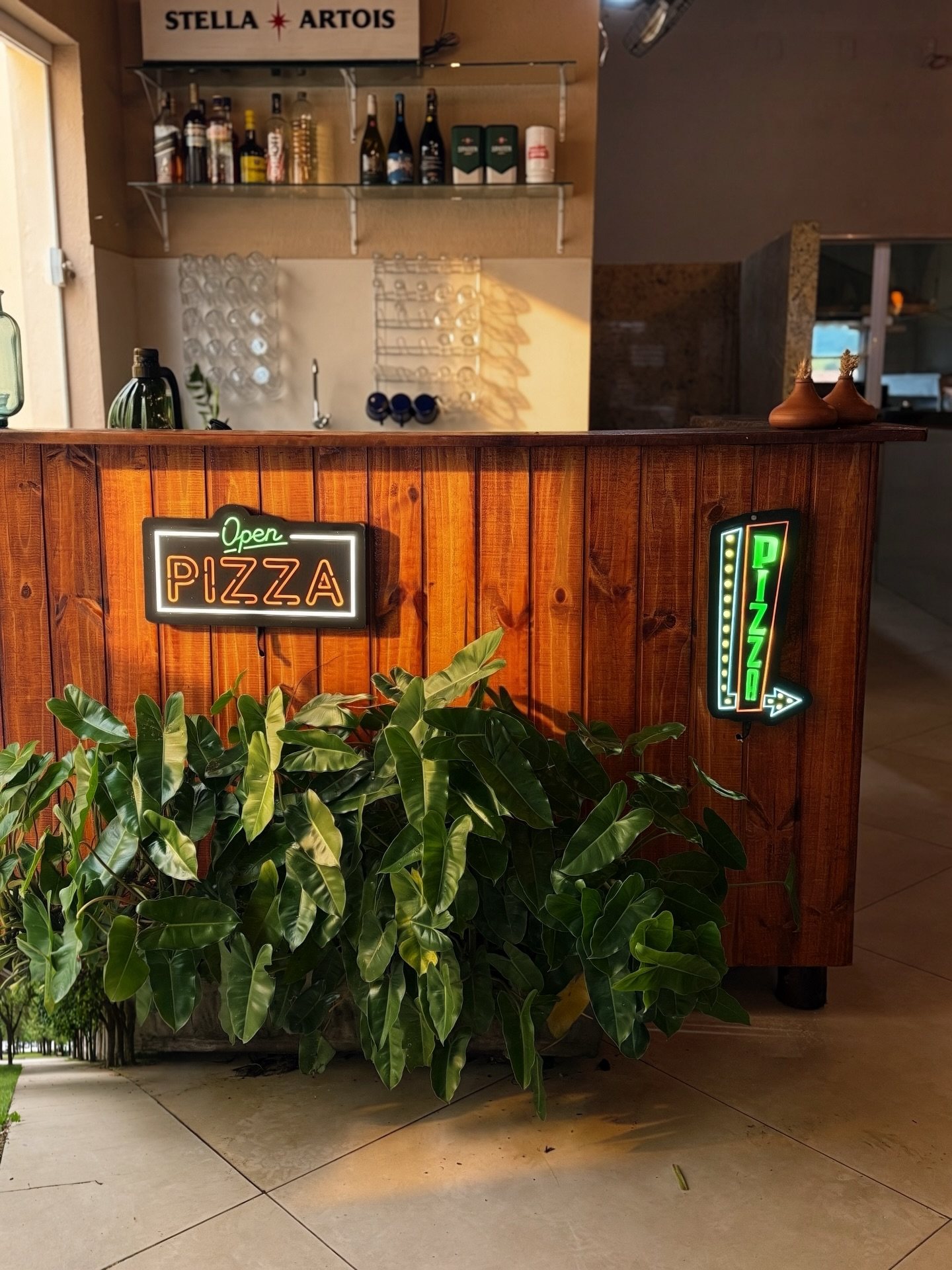 Balcão de madeira com placas de neon escrito pizza