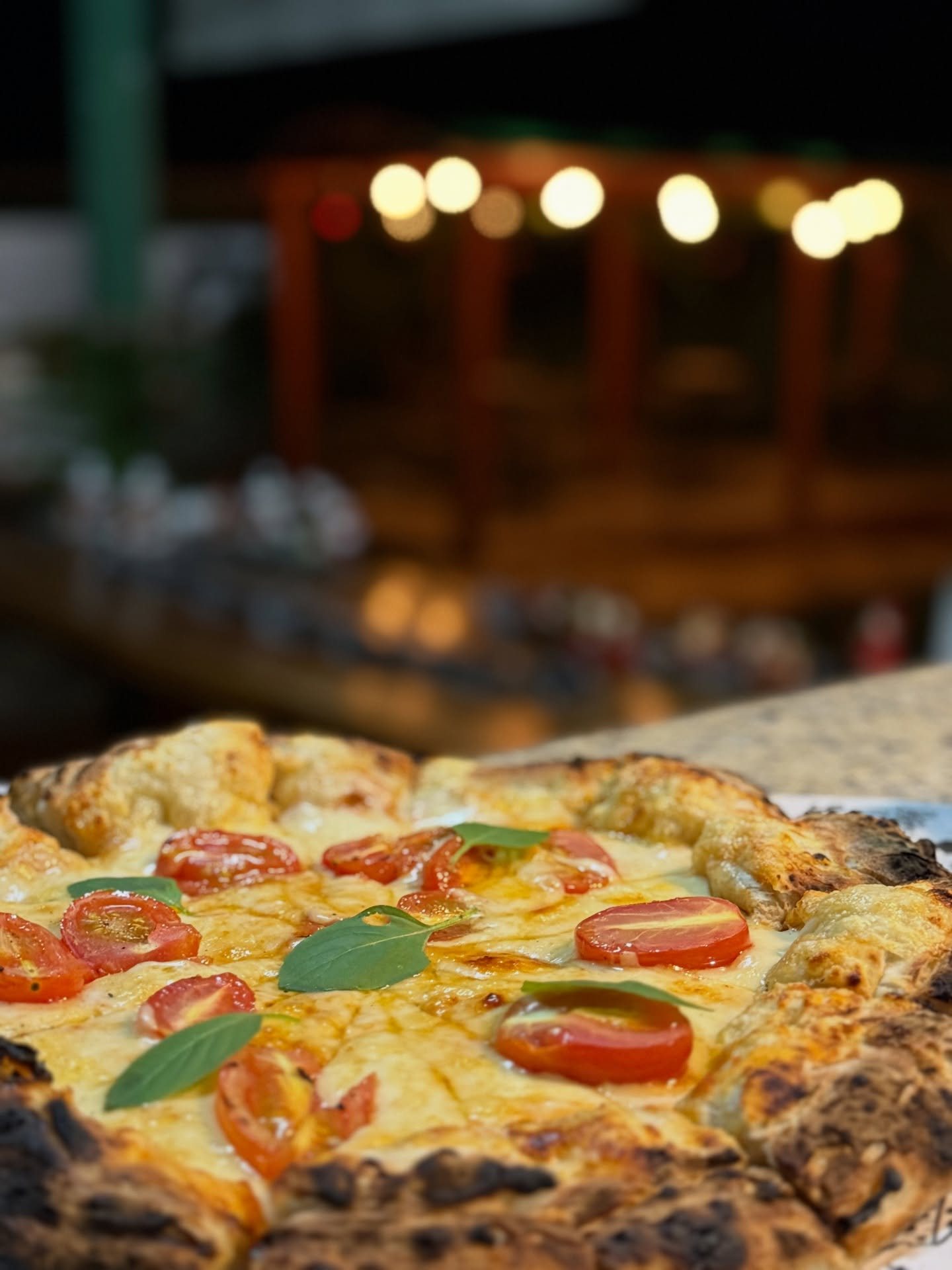 Pizza margherita com tomate-cereja e manjericão saindo do forno